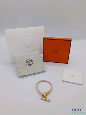 un bracelet orange avec un fermoir doré et une boîte blanche