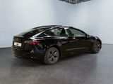 the tesla model 3 is parked in a showroom with a white wall in the background