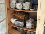 many plates and bowls stacked on the shelves in the pantry