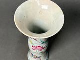 a small white vase with a floral design on it
