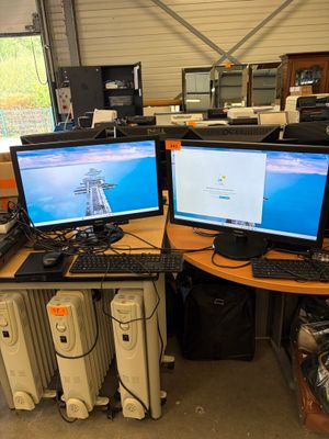 two computer monitors sitting on top of a wooden desk