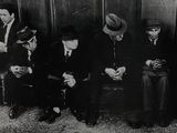 photographie en noir et blanc d'un groupe d'hommes assis les uns à côté des autres
