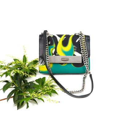 a close up of a purse and a plant on a white surface