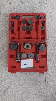 une boîte à outils rouge remplie d'outils, posée sur un sol en béton