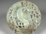 une image représentant une sculpture en jade vert représentant un oiseau posé sur un socle