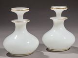 pair of white vases with gold rims sitting on a gray surface
