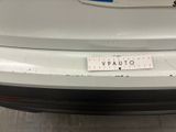 the rear end of a white car with a sticker on it