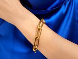 La femme porte une robe bleue et un bracelet doré.