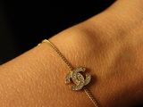 a woman ' s arm with a bracelet that has a diamond heart on it