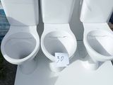 three toilets sitting on a white table outside