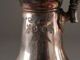 a silver vase that has a handle on it
