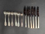 six fourchettes et six couteaux sont alignés sur une table