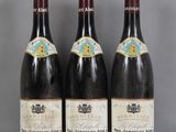 Trois bouteilles de vin sont alignées sur une table en verre