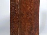an old brown book sitting on top of a table next to a white wall