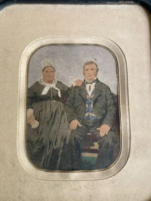 an old picture of a man and woman sitting on a chair
