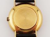a close up of a gold watch with a brown leather strap