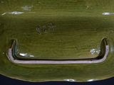 a green bowl with a handle on a black table
