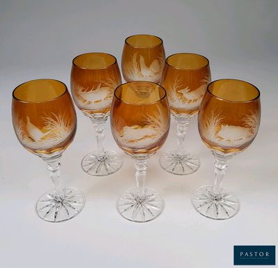 six verres à vin ornés de motifs gravés, posés sur une surface blanche
