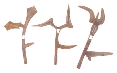 Trois vieux outils sont posés les uns à côté des autres sur une surface blanche