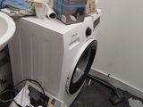 une machine à laver et un sèche-linge dans une salle de bains où se trouve un sac poubelle