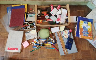 une boîte en bois remplie de fournitures scolaires posée par terre