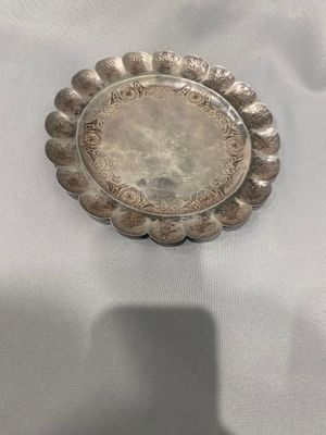 un vieux plat en argent posé sur une nappe blanche