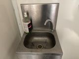a sink in the corner of a bathroom with a soap dispenser