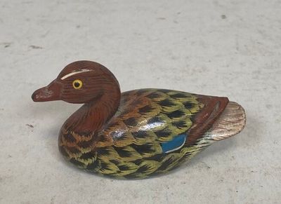 a small wooden duck that is sitting on the ground