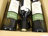 quatre bouteilles de vin dans une boîte en carton posée sur une table