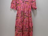 a pink dress hanging on a hanger against a wall