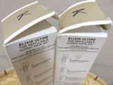 two boxes of elixir ultimate hair oil sitting on top of a wooden table