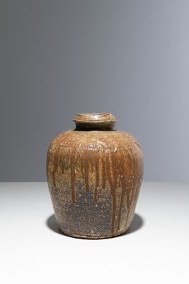 un vase brun posé sur une table à fond gris
