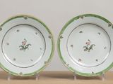 two plates with green and white designs on them on a table