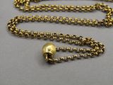 a close up of a gold necklace with a bell on a chain