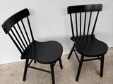 pair of black wooden chairs against a white wall in a room