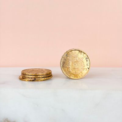 une pièce d'or posée sur un comptoir en marbre, à côté d'une pile de pièces