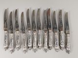 six knives are lined up in a row on a white surface