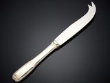 a silver plated knife on a black surface with a black background