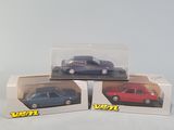 three toy cars are in a box on a white surface