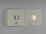 a silver coin in a white box on a table