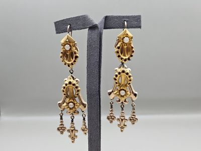 a pair of gold toned earrings with dangling charms