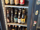 a person standing in front of a refrigerator filled with bottles of beer