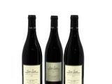 three bottles of wine sitting next to each other on a white surface