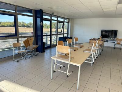 tables and chairs in a room with large windows and a flat screen tv