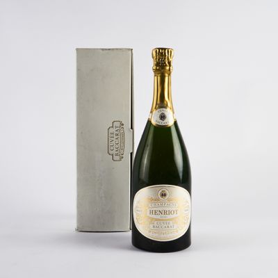 une bouteille de champagne posée à côté d'un coffret en argent sur une surface blanche