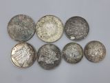 six types différents de pièces d'argent sur une surface blanche