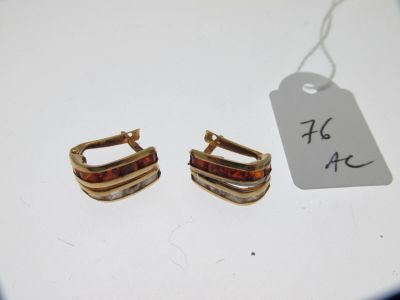 deux paires de boucles d'oreilles en or avec une étiquette sur un fond blanc
