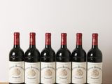 six bottles of red wine lined up on a wooden table