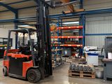 a forklift in a warehouse with a lot of pallets on the floor