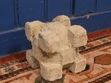 a stone elephant sitting on a rug in front of a blue door